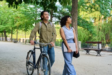 İki genç iş arkadaşı işten çıktıktan sonra parkta yürüyorlar ve konuşuyorlar, temiz havanın tadını çıkarıyorlar ve günlerini tartışıyorlar.