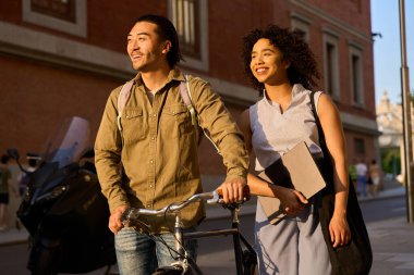 Gün batımında şehir caddesinde yürüyen iki genç öğrenci sohbetin ve batan güneşin sıcacık parıltısının tadını çıkarıyorlar.