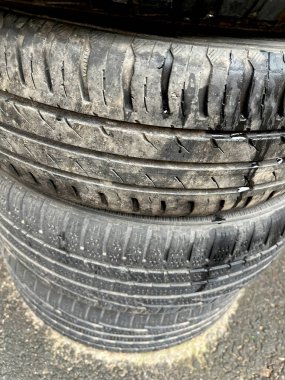 Close-up of stack of dirty car tires on the ground with selective focus on foreground
