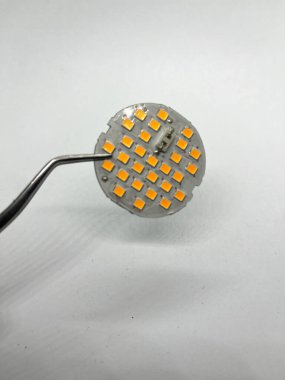 Close-up of board with leds held in a pair of tweezers