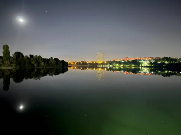Vista Nocturna Árboles Luna Ciudad Reflejándose Agua Del Lago — Foto de Stock