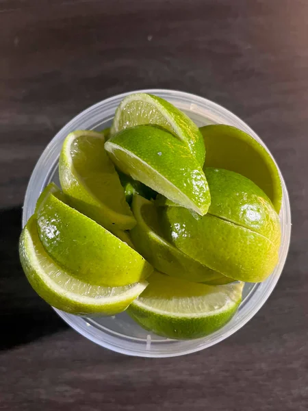 Närbild Gröna Lime Skivor Plastburk Med Trä Bakgrunden — Stockfoto