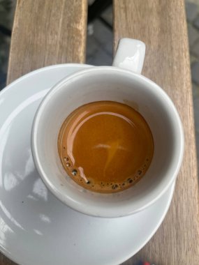 Beyaz bardağa yakın çekim, üzerinde espresso olan tahta bir masa.