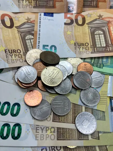 Close-up of Romanian currency coins on Euro banknotes. 5 bani 10 bani 50 bani 50 euro 100 euro