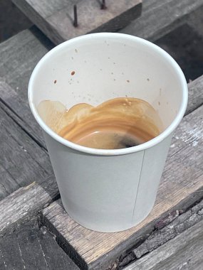 Tahta bir standın üzerinde espresso kahveli beyaz plastik bardağa yakın çekim.