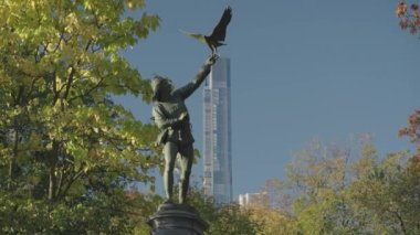Falconer Heykeli. Avcı kuşunu ve Central Park Kulesini Manhattan, New York City, ABD 'de bırakmak için yukarı uzanan bir adam.