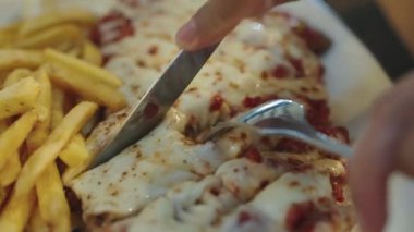 Eritilmiş Mozzarella peyniri, Napoli sosu ve patates kızartmasıyla süslenmiş Parmesanlı Tavuk.