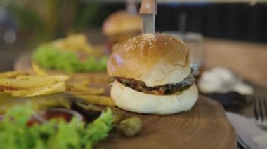 Koca ağızlı adam Austin Texas BBBQ Burger Angus Biftek Patty Mozzarella Hardal ve Patates kızartmalı Soğan halkaları yiyor.