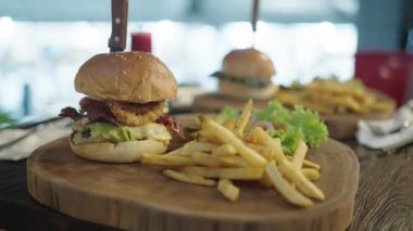 Koca ağızlı adam Austin Texas BBBQ Burger Angus Biftek Patty Mozzarella Hardal ve Patates kızartmalı Soğan halkaları yiyor.