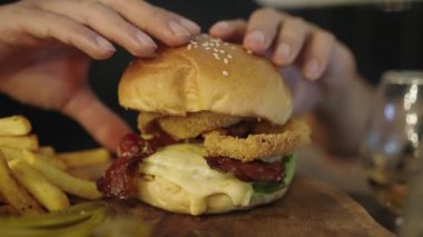 Koca ağızlı adam Austin Texas BBBQ Burger Angus Biftek Patty Mozzarella Hardal ve Patates kızartmalı Soğan halkaları yiyor.