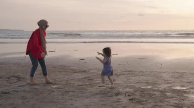 Happy Modern Muslim Southeast Asian Indonesian Family Enjoying Sunset Together on The Beach. Silhouette of Father Mother and Child in Slow Motion.