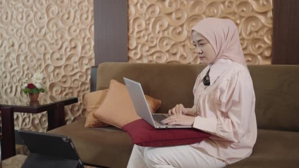 現代のイスラム教徒の女性 ヒジャブ東南アジア ラップトップを通して株式市場への投資グラフィックチャートを表示することで暗号化外国為替 — ストック動画