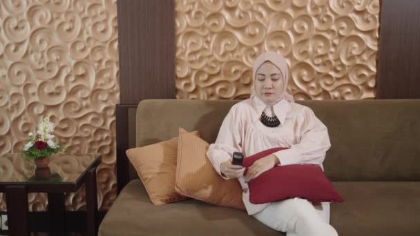 Modern Muslim Woman Hijab Southeast Asian Watching Using Remote While — Vídeo de stock