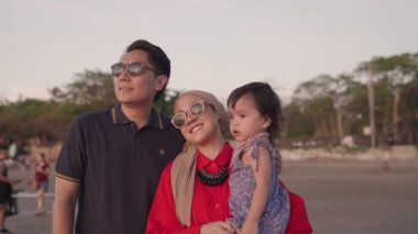 Happy Muslim Indonesian Family Father Mother and Toddler Love Enjoying Sunset Together on The Beach