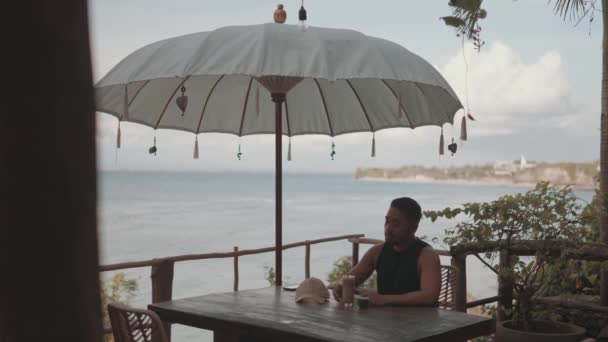 バリ島のビーチでコーヒーを楽しむ男 — ストック動画