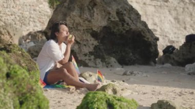 Koyu Derili Güneydoğu Asya LGBT Gay Adam Gökkuşağı Gururlu Piknik Battaniyesiyle Sahilde Oturuyor