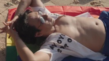 Koyu Derili Güneydoğu Asya LGBT Gay Adam Gökkuşağı Gururlu Piknik Battaniyesiyle Sahilde Oturuyor