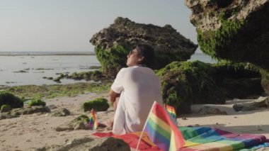 Koyu Derili Güneydoğu Asya LGBT Gay Adam Gökkuşağı Gururlu Piknik Battaniyesiyle Sahilde Oturuyor