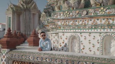 Bir adam Wat Arun 'un mimari detaylarının yanından geçiyor. Wat Arun, Tayland 'ın Bangkok kentinde Chao Phraya nehrinin kıyısında yer alan ünlü bir Budist tapınağıdır..