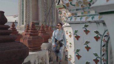 Bir adam Wat Arun 'un mimari detaylarının yanından geçiyor. Wat Arun, Tayland 'ın Bangkok kentinde Chao Phraya nehrinin kıyısında yer alan ünlü bir Budist tapınağıdır..