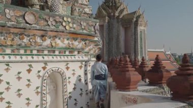 Bir adam Wat Arun 'un mimari detaylarının yanından geçiyor. Wat Arun, Tayland 'ın Bangkok kentinde Chao Phraya nehrinin kıyısında yer alan ünlü bir Budist tapınağıdır..