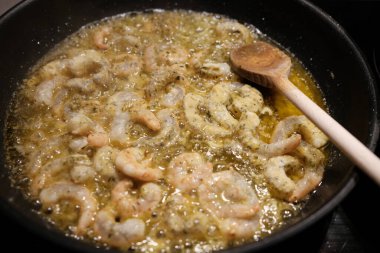 Tavada baharatlı kızarmış karides pişirmek.