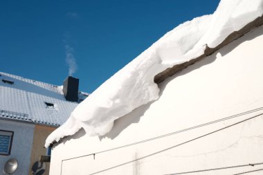 Güneşli bir günde evin çatısında kar yağar.
