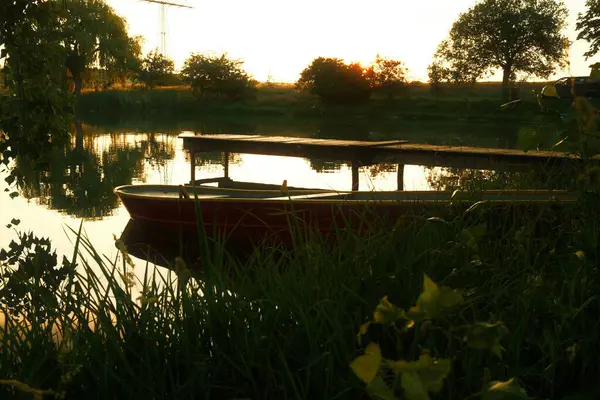 日落时停泊在湖边木制码头附近的一艘船的漂亮镜头 — 图库照片