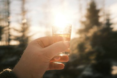 Bir adam elinde bir bardak içki tutar kışın bulanık arka planına karşı