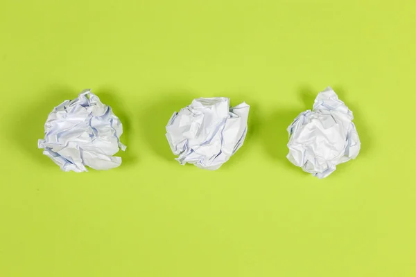 white crumpled paper balls on green background