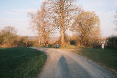 Sırt çantalı insanlar kediye bakıyor ve kırsalda dinleniyorlar.