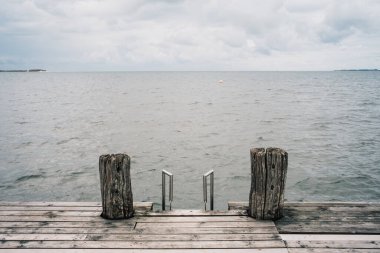 Göl üzerinde ahşap iskele ve bulutlu gökyüzü