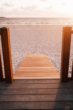 Gün batımında kumlu sahilde ahşap yol