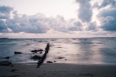 Bulutlu bir günde deniz ve kumlu sahil manzarası