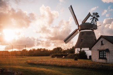 Günbatımında gökyüzü olan eski yel değirmeni manzarası