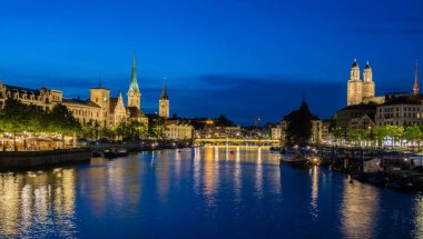 Ünlü Fraumnster ve Grossmnster Kilisesi ve İsviçre 'nin Zürih Gölü' ndeki Limmat nehri ile tarihi şehir merkezinin panoramik manzarası. Gece fotoğrafı