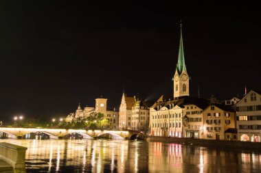 Ünlü kiliseleri ve İsviçre 'nin Zürih Gölü' ndeki Limmat nehri ile tarihi Zürih şehir merkezinin manzaralı manzarası. Gece fotoğrafı