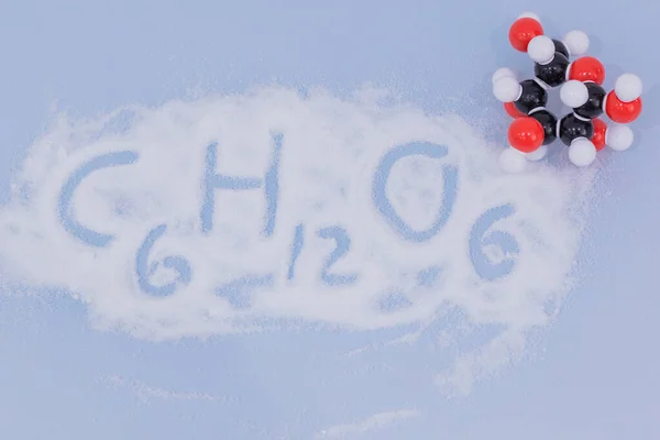 Isolated glucose molecule made by molecular model with glucose formula written on white sugar. C6H12O6 sugar chemical formula with colored atoms and bonds