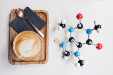 Kafein (ya da theine) moleküler model tarafından sütlü kahve fincanının yanında latte sanatıyla birlikte üretilir. Renkli atomlar ve bağlarla kahve ve çay kimyasal formülü