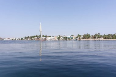 Aswan, Mısır; 04 25 2023: Nil Nehri 'nin Nil yolcu gemisinden bir yelkenliyle çekilmiş resmi. Felucca, Mısır 'da kullanılan tipik bir ahşap teknedir..