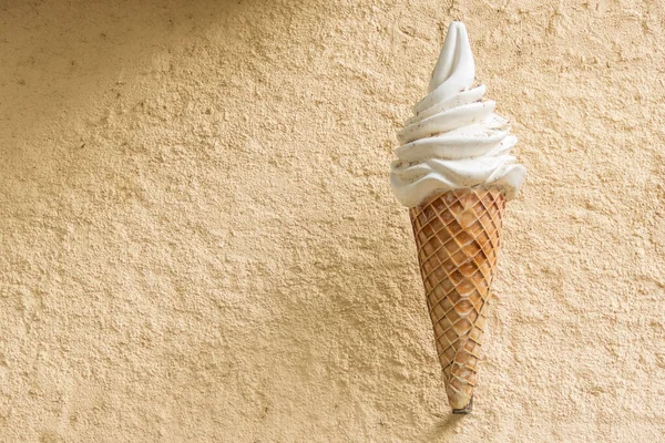 Giant ice cream cornet figure on beige rough wall. Ice cream shop commercial advertising.