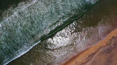 Goa deniz dalgalarının kumlu sahil şeridinde kırılışının kusursuz güzel görüntülerinin insansız hava aracı görüntüsü. Derin mavi okyanus suyu ve köpüklü dalgalarla dolu altın plaj.