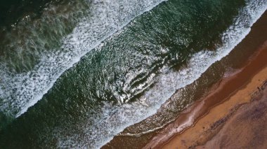Goa deniz dalgalarının kumlu sahil şeridinde kırılışının kusursuz güzel görüntülerinin insansız hava aracı görüntüsü. Derin mavi okyanus suyu ve köpüklü dalgalarla dolu altın plaj.