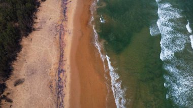 Goa deniz dalgalarının kumlu sahil şeridinde kırılışının kusursuz güzel görüntülerinin insansız hava aracı görüntüsü. Derin mavi okyanus suyu ve köpüklü dalgalarla dolu altın plaj.