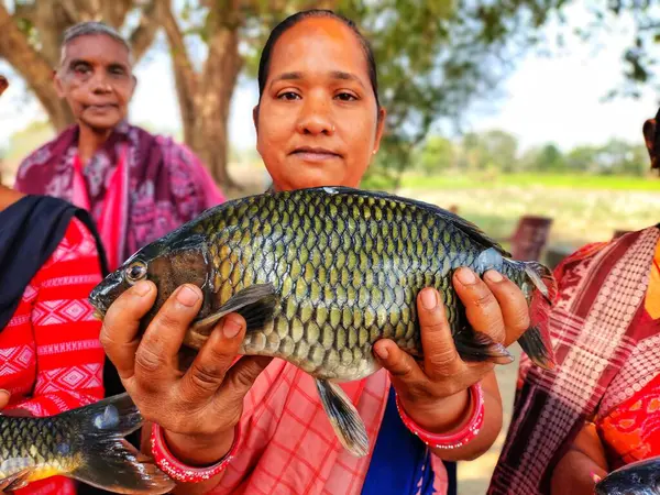 Mutlu kadın balık çiftçisi. Büyük balığı elinde tutan yardım grubu.