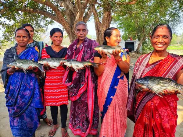 Mutlu kadın balık çiftçisi. Büyük balığı elinde tutan yardım grubu.