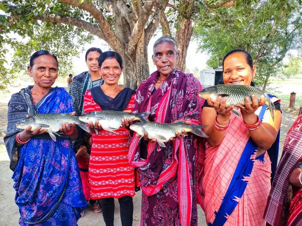 Mutlu kadın balık çiftçisi. Büyük balığı elinde tutan yardım grubu.