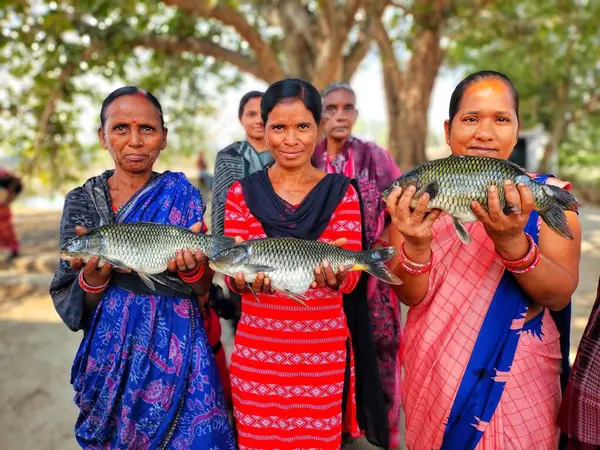 Mutlu kadın balık çiftçisi. Büyük balığı elinde tutan yardım grubu.