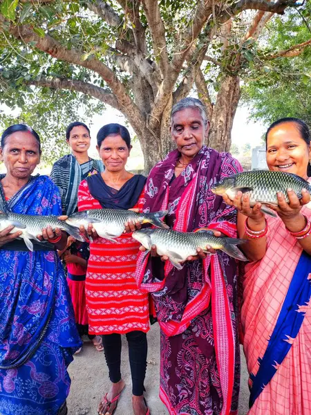 Mutlu kadın balık çiftçisi. Büyük balığı elinde tutan yardım grubu.