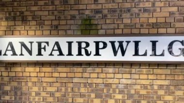 Llainfair PG, Wales, İngiltere -2023: Llanfair pwllgwyngyllgwyngyllgogerychwyrndrobwllllantysiliogogogoch, veya Llanfair Pwllgwyngyll sign. Kasıtlı olarak en uzun isim kasabaya verildi.. 